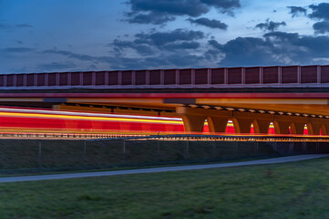 car tail lights long under a bridge on motorway