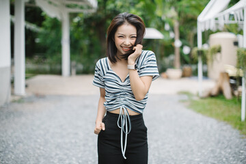 Summer sunny lifestyle fashion portrait of young stylish hipster Asia woman walking on the street, wearing cute trendy outfit