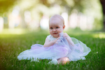 Cute little girl in the grass in summer day