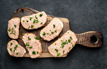 Fototapeta premium Chicken pate on toast with fresh parsley on a cutting board on a stone background