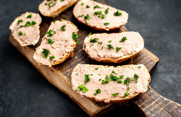 
Chicken pate on toast with fresh parsley on a cutting board on a stone background