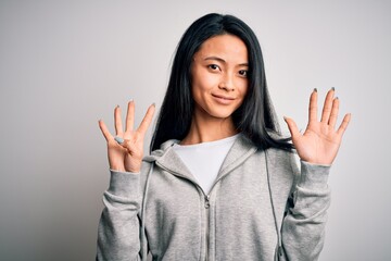 Young beautiful chinese sporty woman wearing sweatshirt over isolated white background showing and pointing up with fingers number nine while smiling confident and happy.