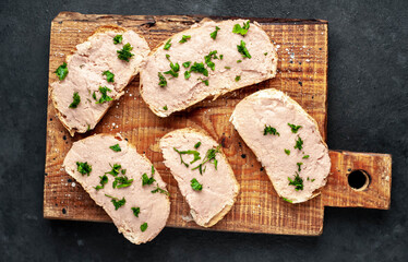 
Chicken pate on toast with fresh parsley on a cutting board on a stone background