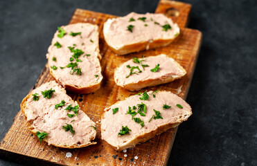
Chicken pate on toast with fresh parsley on a cutting board on a stone background
