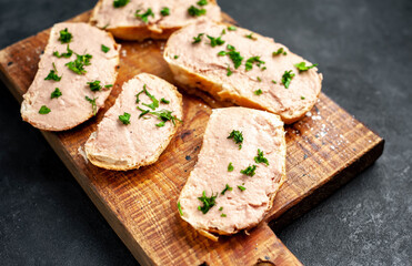 
Chicken pate on toast with fresh parsley on a cutting board on a stone background