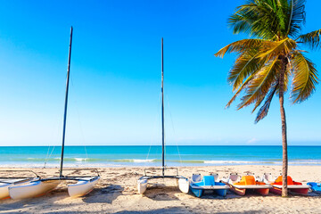 The tropical beach of Varadero in Cuba with sailboats and palm tree on a summer day with turquoise...