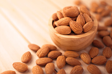 organic peeled brown almonds in wooden bowl on wood table. concept of vegan raw ingredient for vegetarian, snack and healthy food.