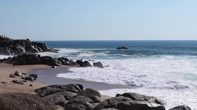 The coast of the Atlantic Ocean.
Static camera. Clean, azure, sandy beach with a rocky ledge.