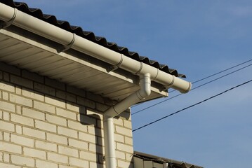 plastic white gutter pipes on the wall of the house under the roof