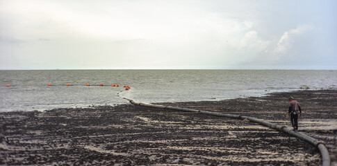 Lonely worker walking on the muddy beach in the south of Thailand