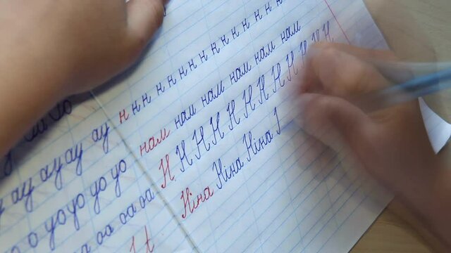 Writing in Ukrainian language cursive letters NINA word (female name). Accelerated footage of a pupil training to write words, syllables and alphabet letters in the copybook