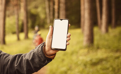 Phone in the hand of a woman in the woods