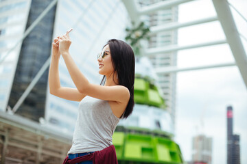 Young Woman Taking Photos Of Cityscape With Mobile Smart Phone