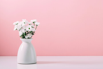 Home interior floral decor. Beautiful flowers in vase on pink wall background.