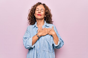 Middle age beautiful woman wearing casual denim shirt standing over pink background smiling with...