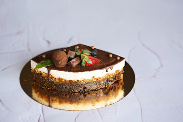 quarter of a chocolate cake Snickers on a white background on a gold background decorated with chocolate, sweets, fresh berries