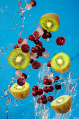 Fototapeta na wymiar Falling fresh mixed fruits. Slices of the kiwi and cherry with fresh water in the air