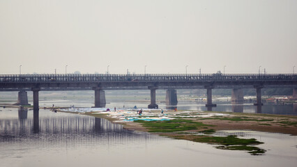 Fototapeta na wymiar bridge over the Yamuna river and an island where Laundry is dried, India