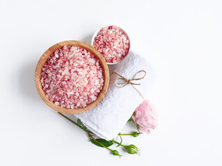 Spa flatlay composition. Sea salt in wooden jar, towel, flower on white background. Top view. Daily care concept, relax and rest, bath procedure