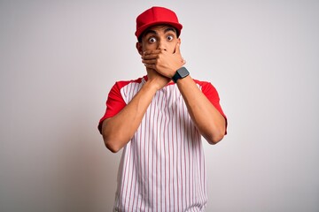 Young handsome african american sportsman wearing striped baseball t-shirt and cap shocked covering mouth with hands for mistake. Secret concept.