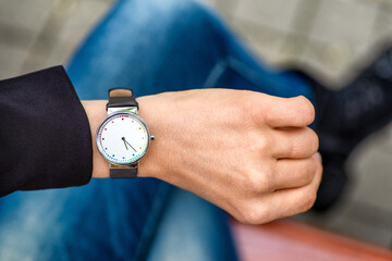 What time is it. Silver wristwatch on hand of woman.