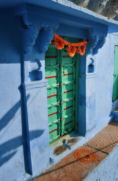 Green Doors Gate To A Blue House With Orange Flowers In Jodhpur, India