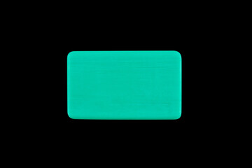 a bar of green blue color soap isolated on a black background close up top view