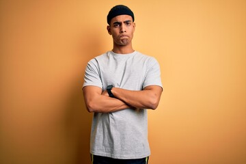 Handsome african american sportsman doing sport wearing sportswear over yellow background skeptic...