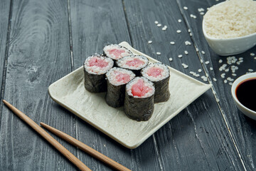 Classic japanese sushi rolls - maki rolls with tuna on a white, ceramic plate on a black wooden background