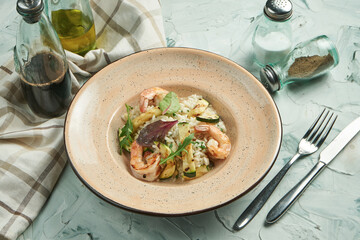 A classic Italian dish - risotto with shrimp and vegetables in a beige plate on a concrete background. Close up. Selective focus