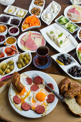 Traditional Turkish Spreading Breakfast on the wooden table.Egg with sausage in white plate in front of breakfast table.Vertical image.