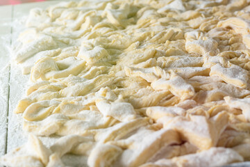 kitchen table. Sprinkled with flour. On it are dough products. Brushwood. Close-up