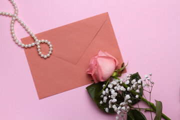 Flat lay of a rose and an envelope on a pink background, close-up. Wedding design, greetings, invitations, Wallpapers.