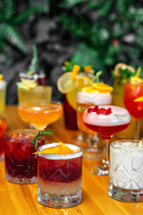 Set of alcoholic multicolor cocktails with fruits on the wooden table.