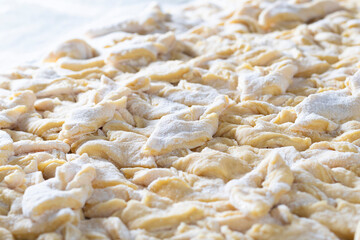 kitchen table. Sprinkled with flour. On it are dough products. Brushwood. Close-up
