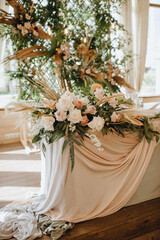 The table of the newlyweds, the presidium, with a gray linen tablecloth, a composition of flowers,...