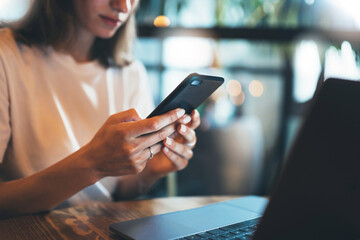 young female manager holding smartphone using laptop office, hipster girl freelancer writing on...