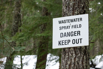 "Wastewater spray field. Danger Keep Out" sign on a tree in a forest