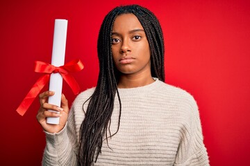 Young african american student girl holding university diploma over red isolated background with a confident expression on smart face thinking serious