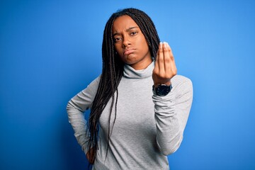 Fototapeta premium Young african american woman standing wearing casual turtleneck over blue isolated background Doing Italian gesture with hand and fingers confident expression