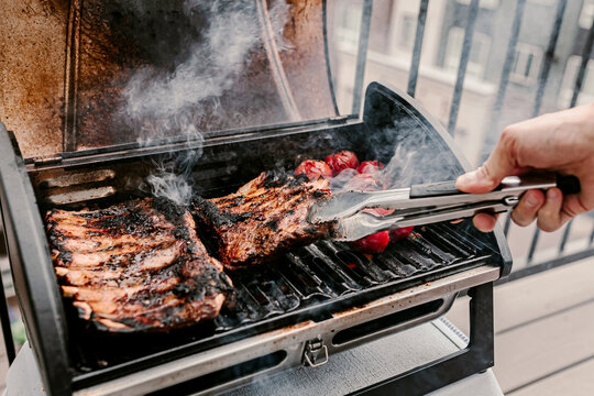 American Style Barbeque Dinner. Gas Grill. Making Smoked Food On Balcony. Grilled Pork Ribs. Red Tomatoes. Charcoal Bbq. Fourth Of July. Independence Day Lunch. Family Holiday Meal. Backyard Party