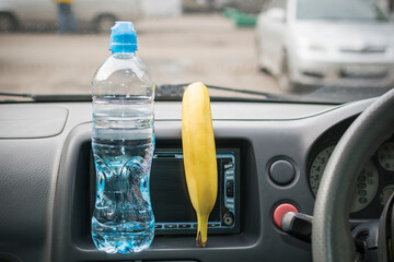 A bottle of water and a banana inside the car.