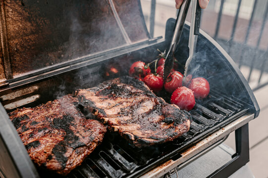 American Style Barbeque Dinner. Gas Grill. Making Smoked Food On Balcony. Grilled Pork Ribs. Red Tomatoes. Charcoal Bbq. Fourth Of July. Independence Day Lunch. Family Holiday Meal. Backyard Party