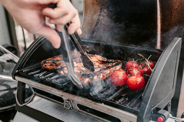American style barbeque dinner. Gas grill. Making smoked food on balcony. Grilled pork ribs. Red tomatoes. Charcoal bbq. Fourth of July. Independence day lunch. Family holiday meal. Backyard party