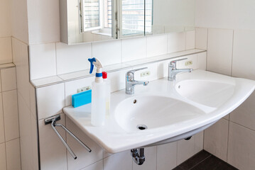clean and bright modern bathroom with cleaning supplies on the sink