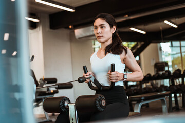 Fototapeta na wymiar Young beautiful woman in sportswear working out with machine in gym