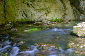 Naklejka na ściany i meble river flowing from a cave