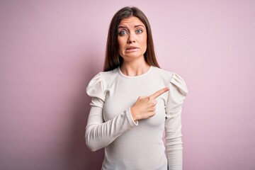 Young beautiful woman with blue eyes wearing casual white t-shirt over pink background Pointing...