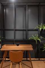 Stylish loft working corner with wood table, leather chair and artificial plant with black metal rod on the background / interior design concept / scandinavian interior
