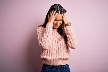 Young beautiful brunette woman wearing casual sweater over isolated pink background suffering from headache desperate and stressed because pain and migraine. Hands on head.